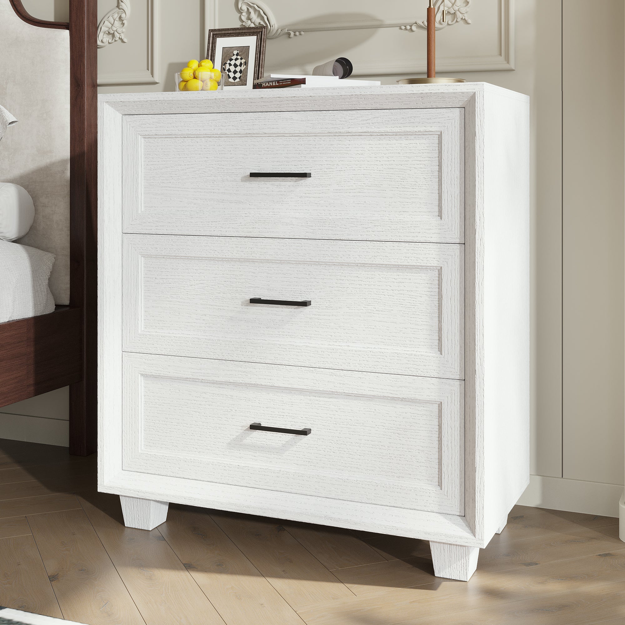 White 3-drawer nightstand with raised panel fronts and black handles