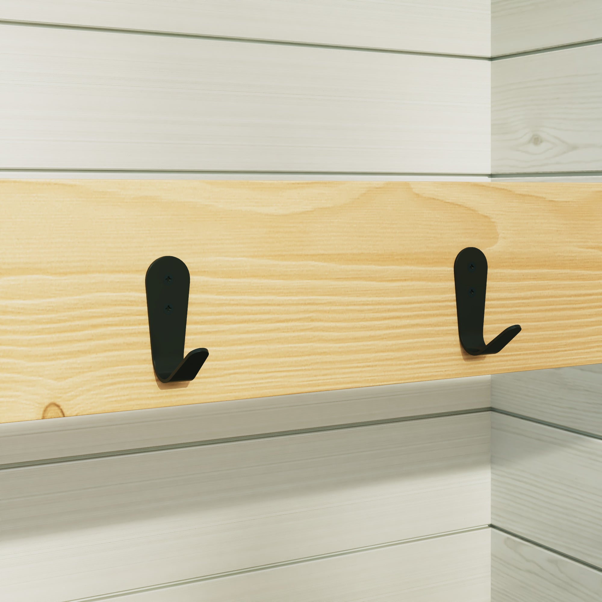 Two black hooks on a wooden shelf against a white wall