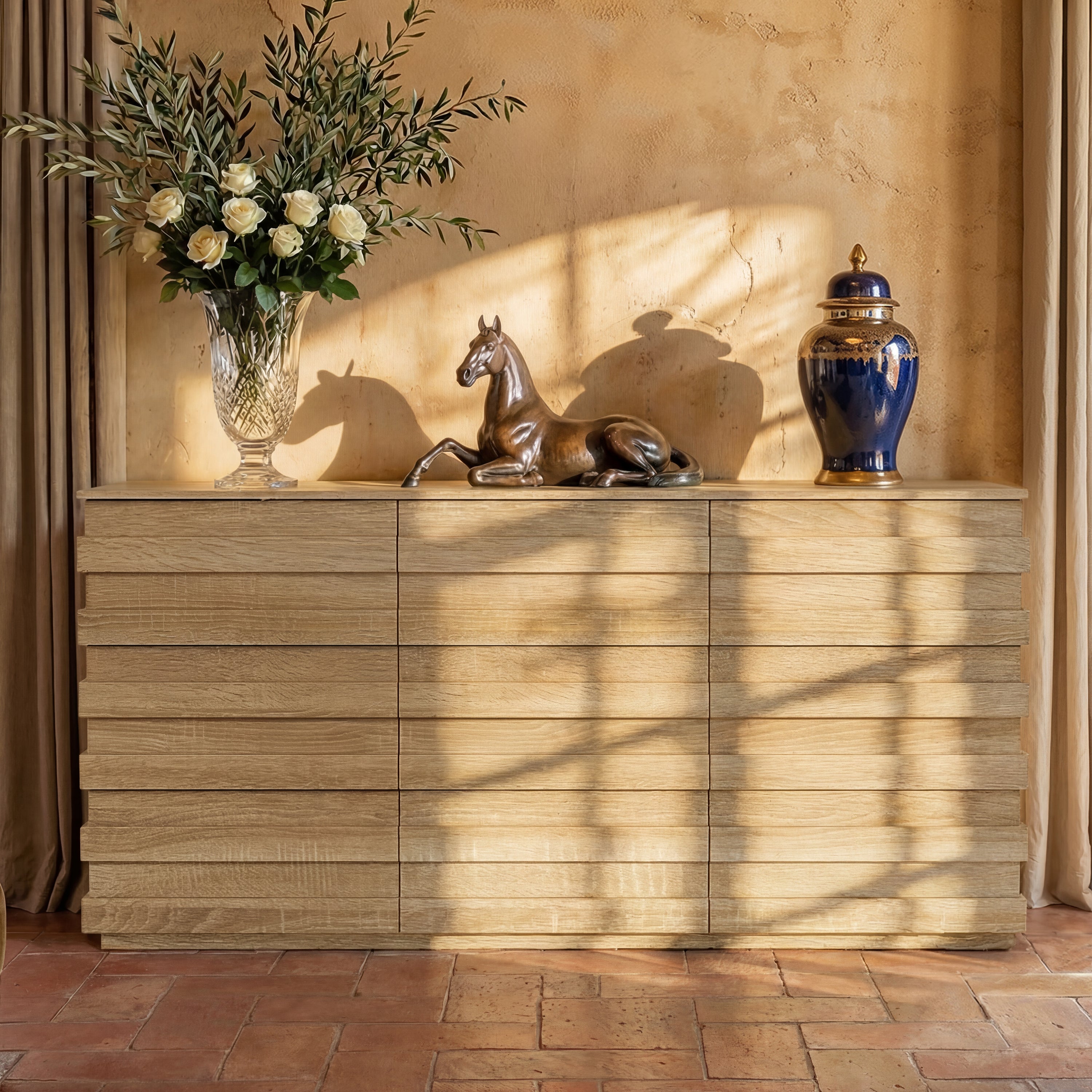 Wooden sideboard with decorative items including a vase, horse statue, and blue urn against a beige wall