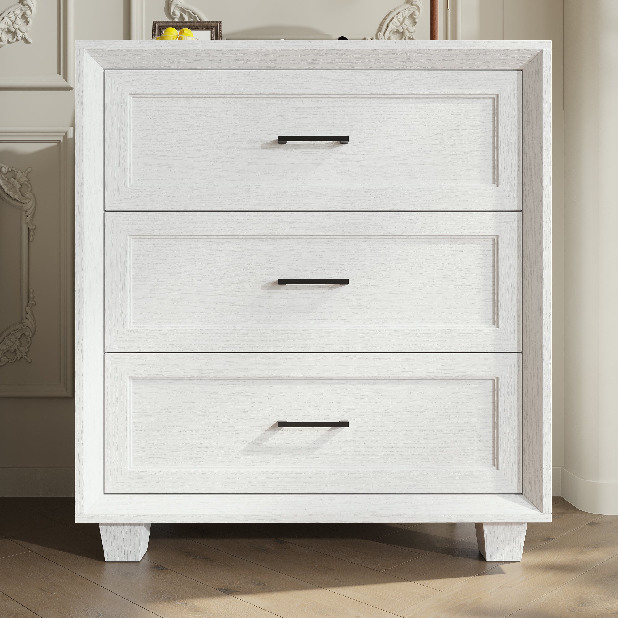 White 3-drawer nightstand with raised panel fronts and black handles