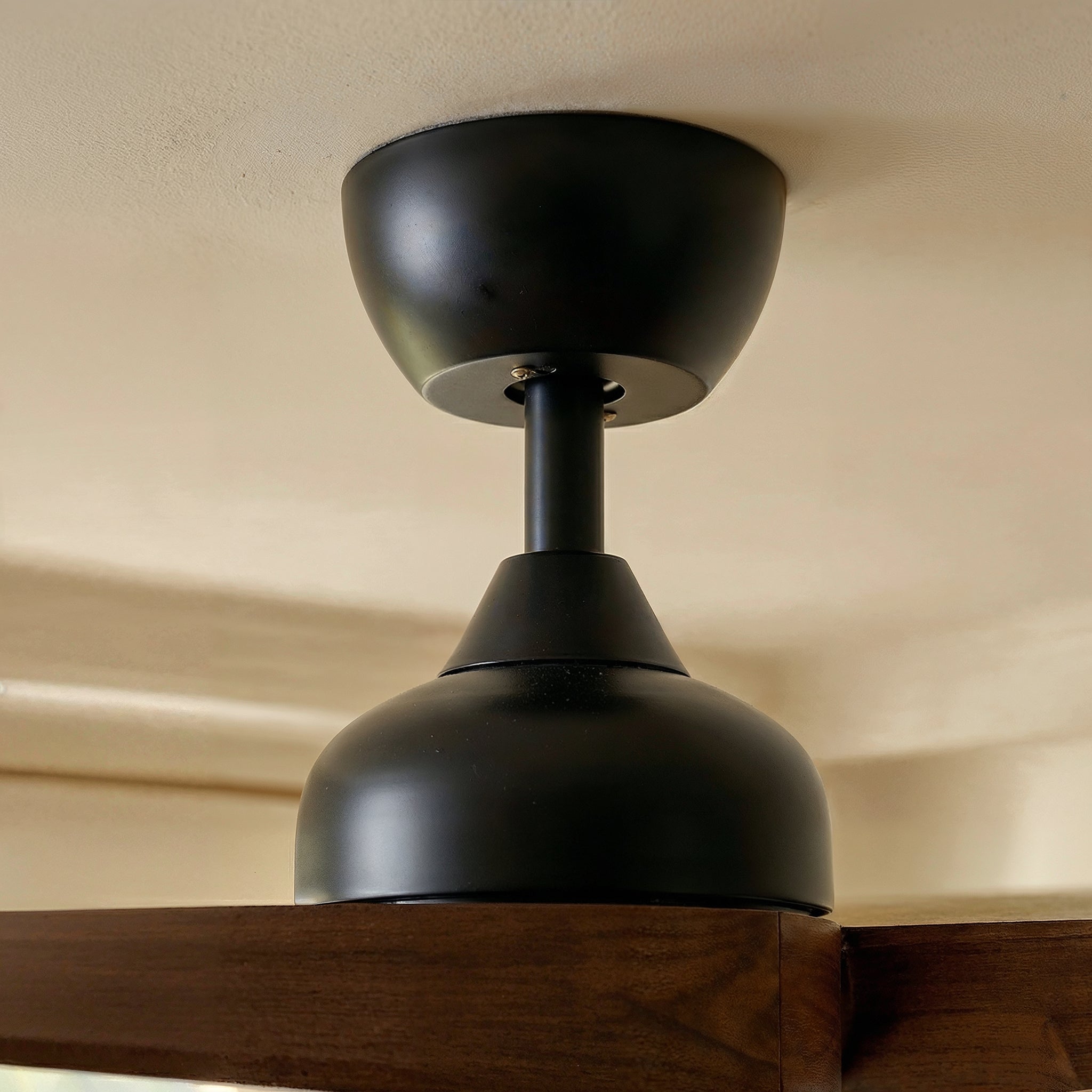 Black ceiling light fixture on a beige wall