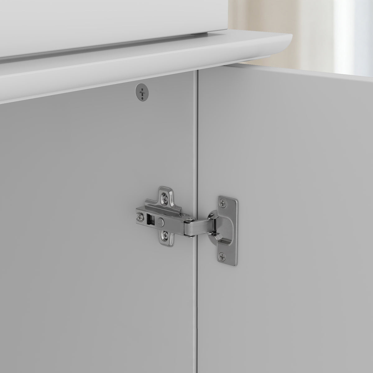 Close-up of a cabinet door hinge on a white cabinet