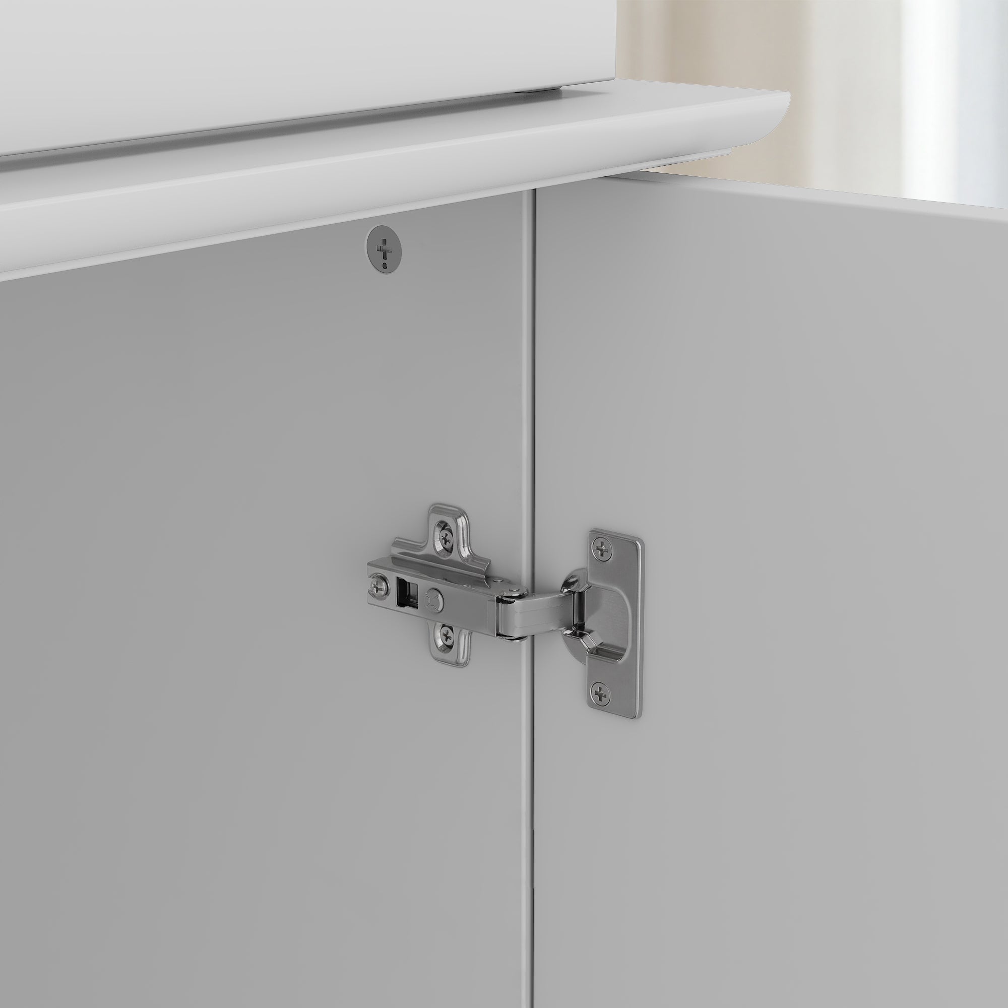 Close-up of a cabinet door hinge on a white cabinet