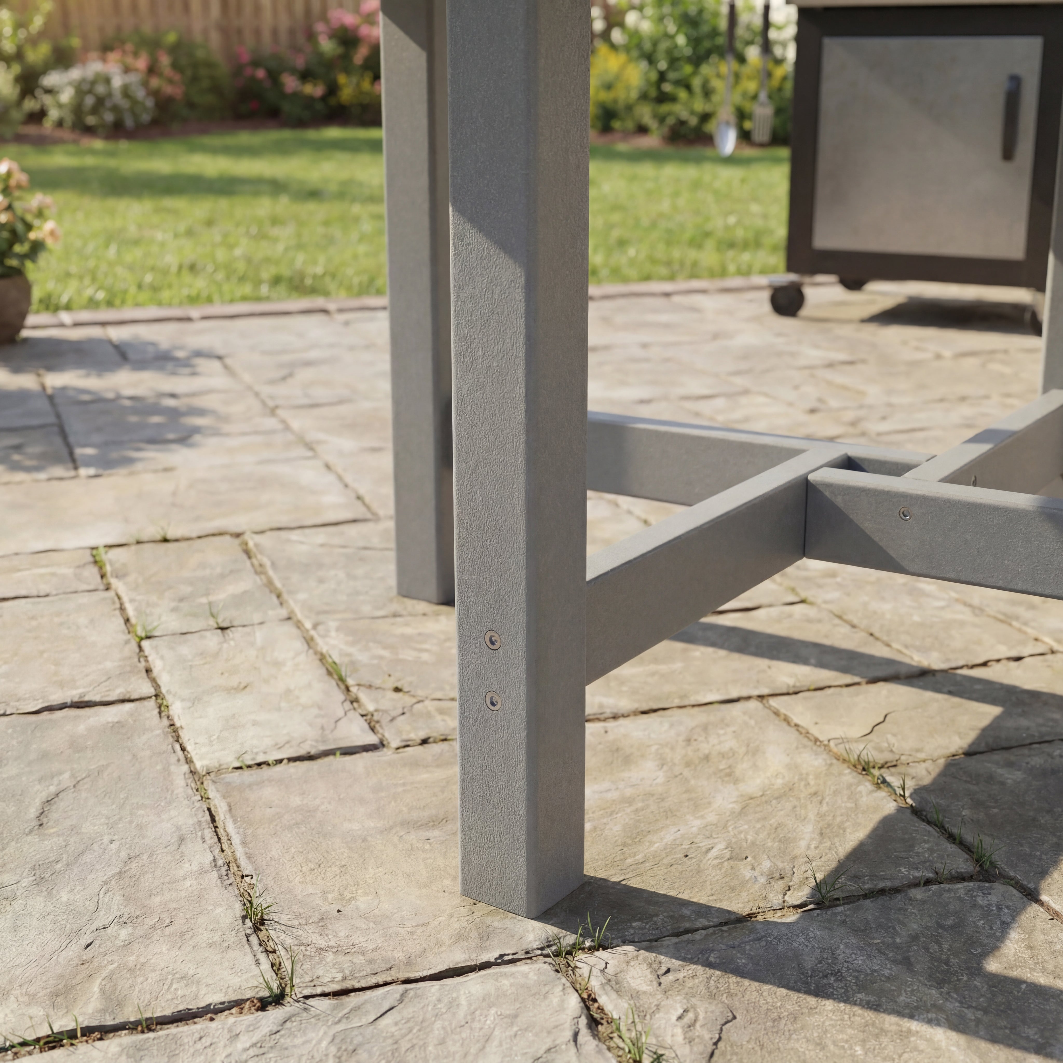 Gray metal outdoor furniture leg on a stone patio with garden background