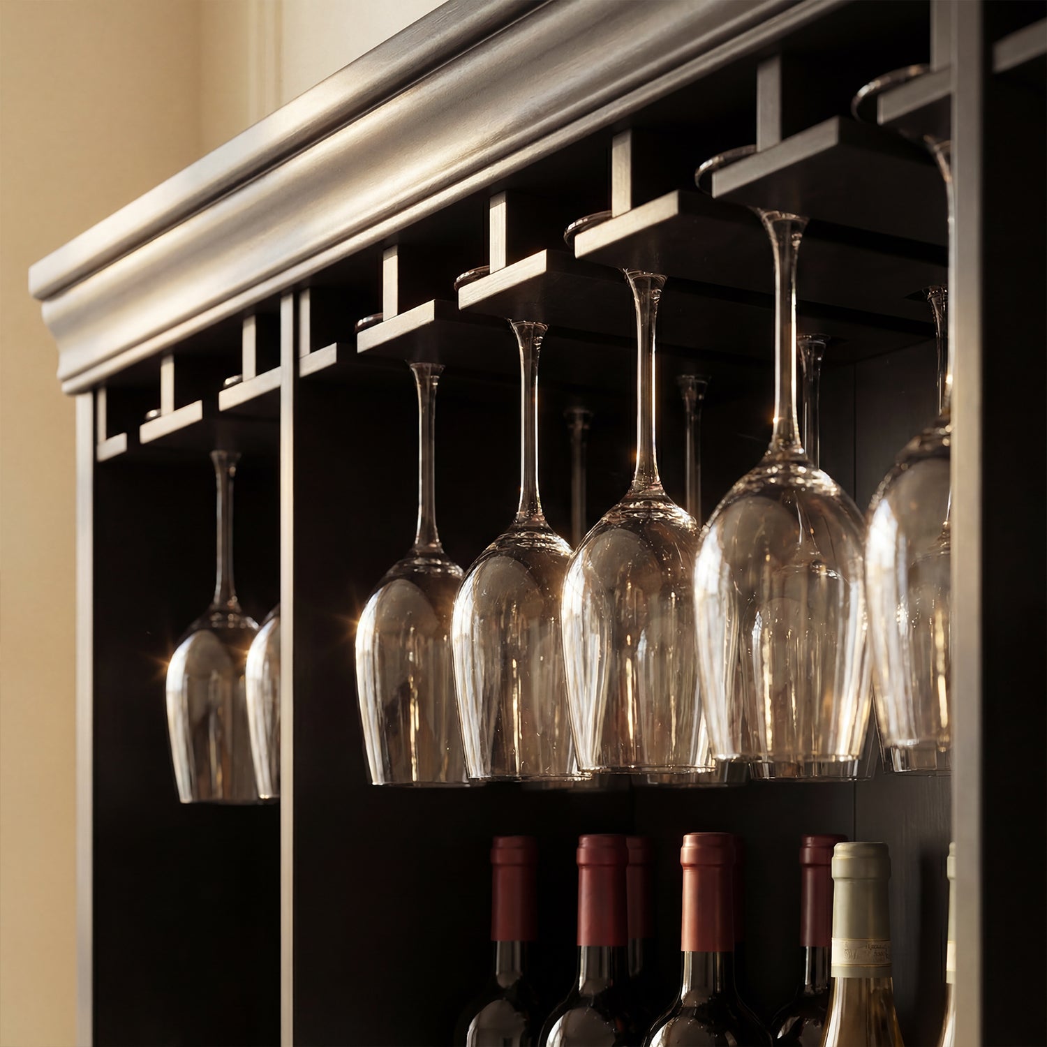 Wine glasses hanging from a rack above wine bottles in a cabinet.