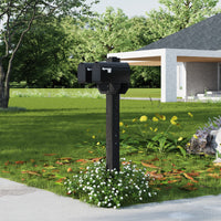 Black mailbox on a post in a garden with a house in the background