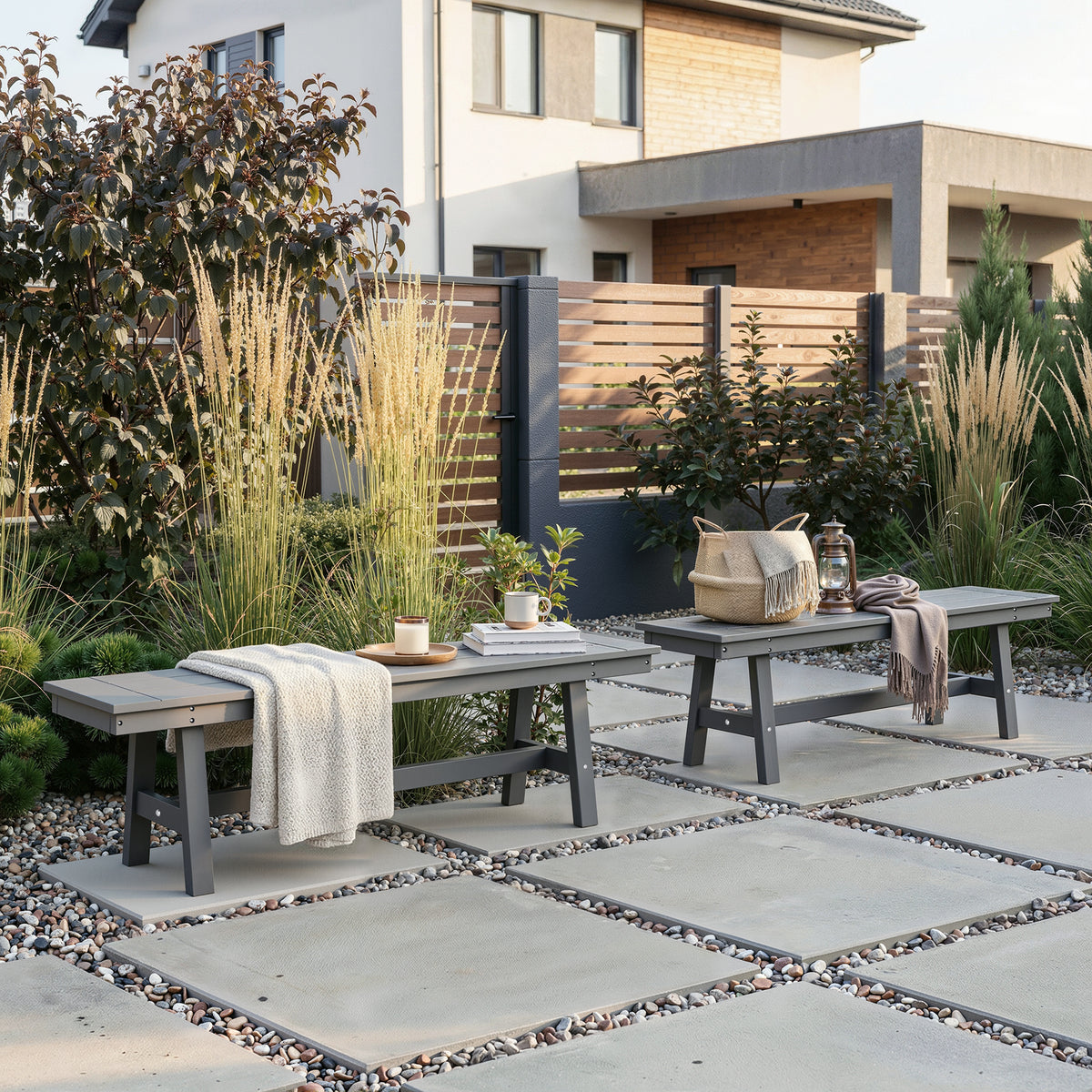 Outdoor patio with two wooden benches, plants, and a lantern on a stone patio.