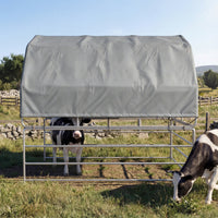 Cows under a gray cover in a grassy field with a clear blue sky