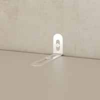 Metal bracket on a beige surface with a textured beige wall background