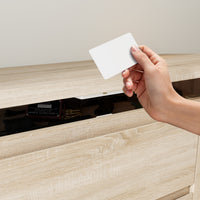 Hand holding a white card above a wooden surface with a drawer