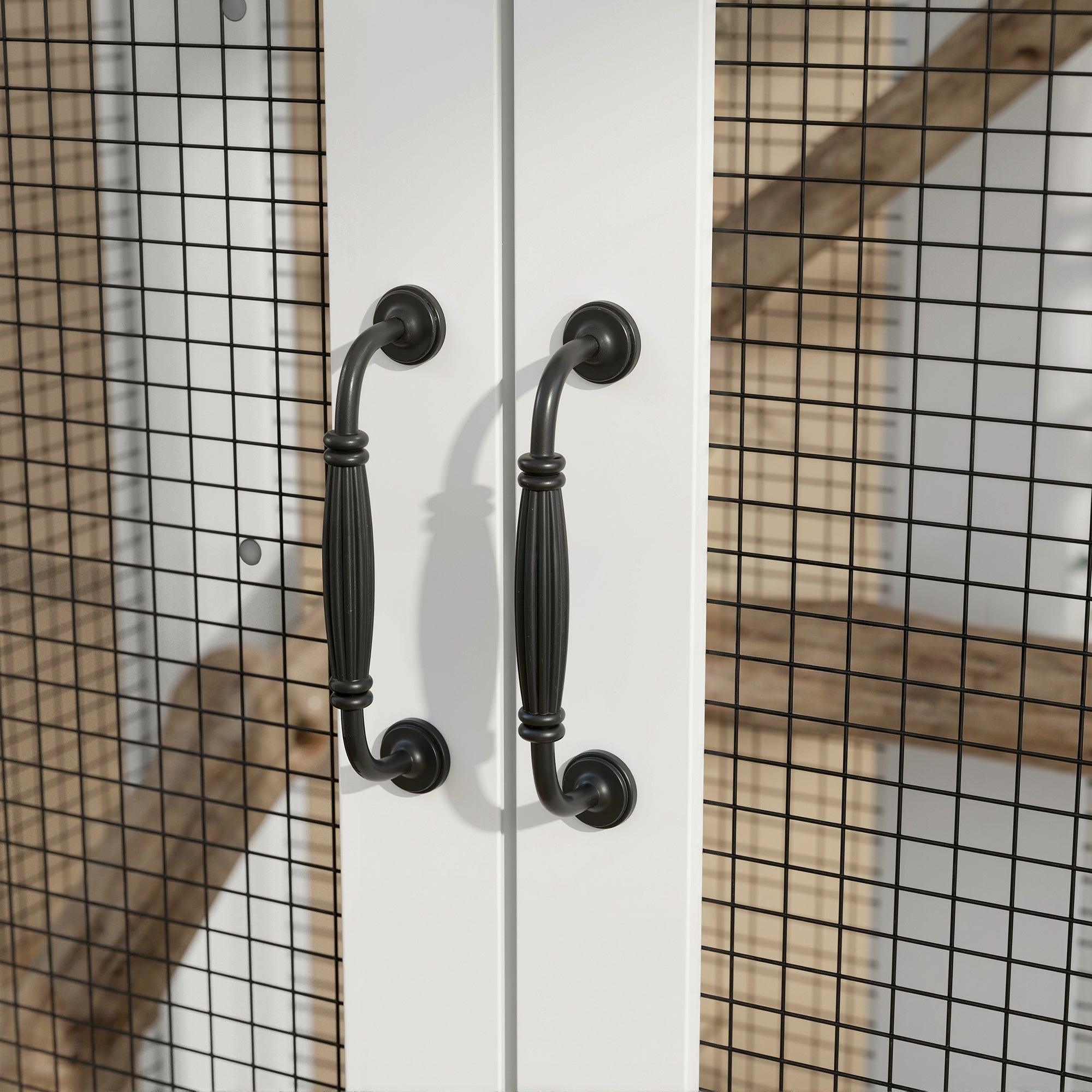 Black metal cabinet handles on a white door with a grid-patterned background