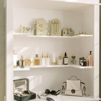 Shelving unit with beauty products, jewelry, and a handbag against a neutral wall.