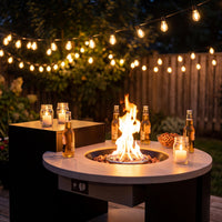 An outdoor fire pit table with a crackling fire, drinks, and snacks, set up on the balcony.