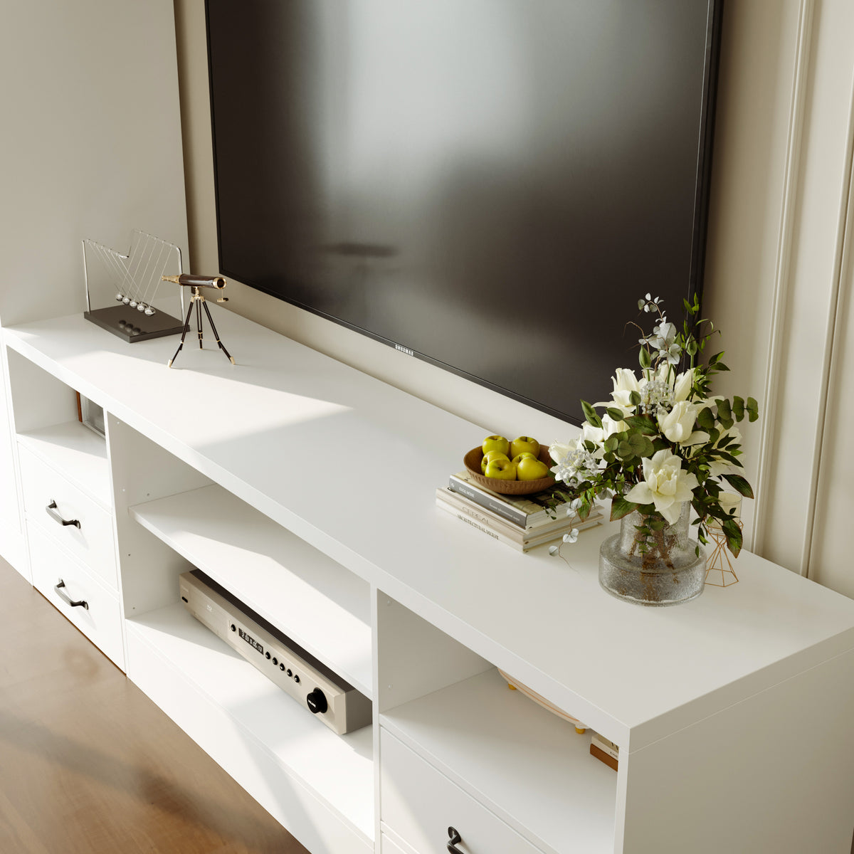 White entertainment console with a television, decorative items, and a vase of flowers.