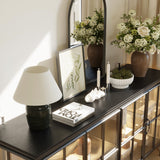 Decorative console table with flowers, lamp, and books in a home setting