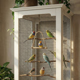 Birdcage with colorful birds inside, placed on a white cabinet.