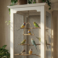 Birdcage with colorful birds inside, placed on a white cabinet.