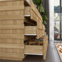 Wooden dresser with multiple drawers in a room with a plant and window