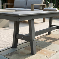 Gray outdoor dining table on a patio with books and a cup on top