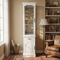 White birdcage with birds inside in a room with a bookshelf and chair.