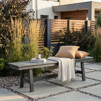 Outdoor bench with pillows and a blanket in a garden setting