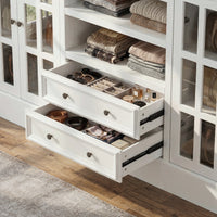 White kitchen island with glass cabinet doors, open shelves, and center drawers