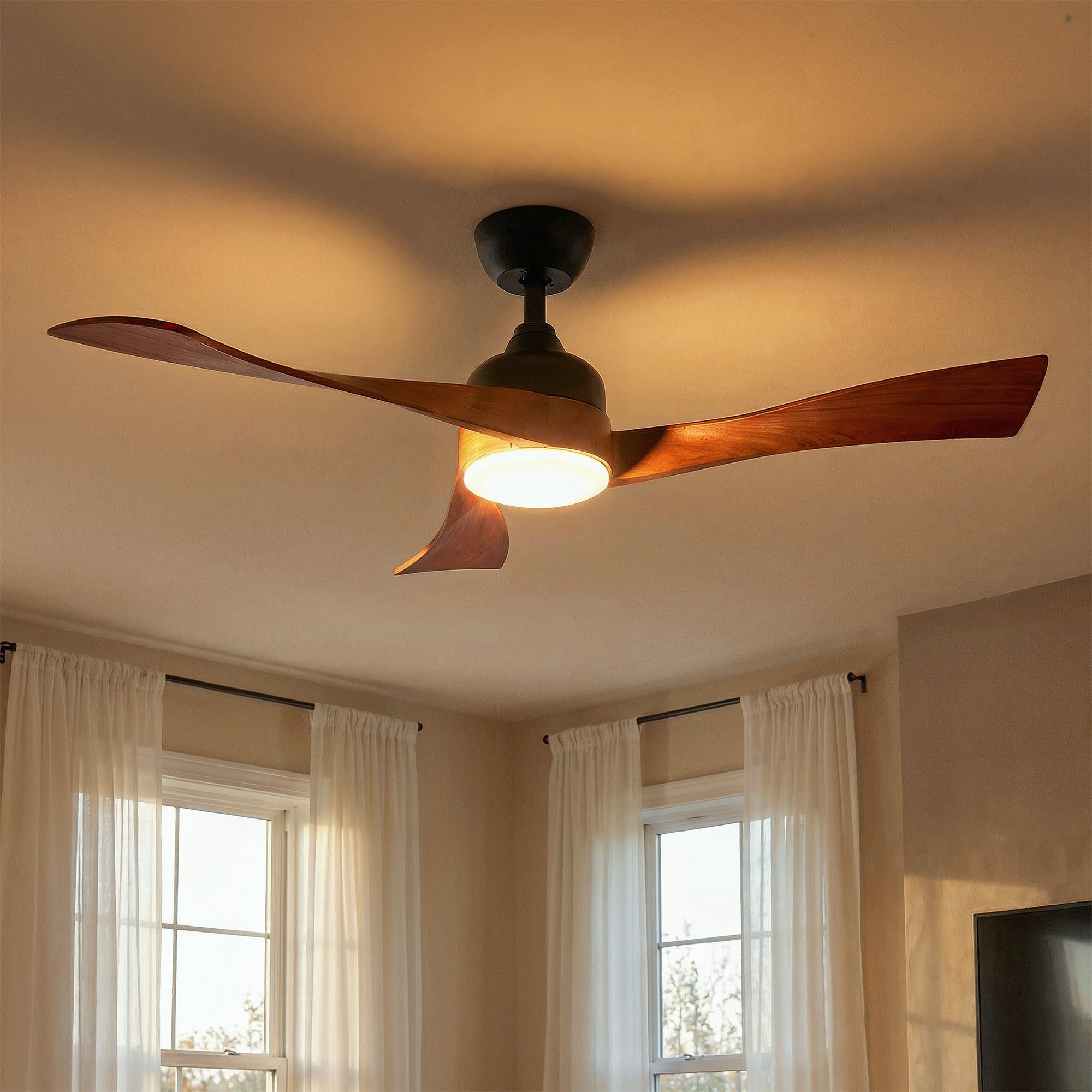 Ceiling fan with wooden blades and light fixture in a room with windows and curtains.