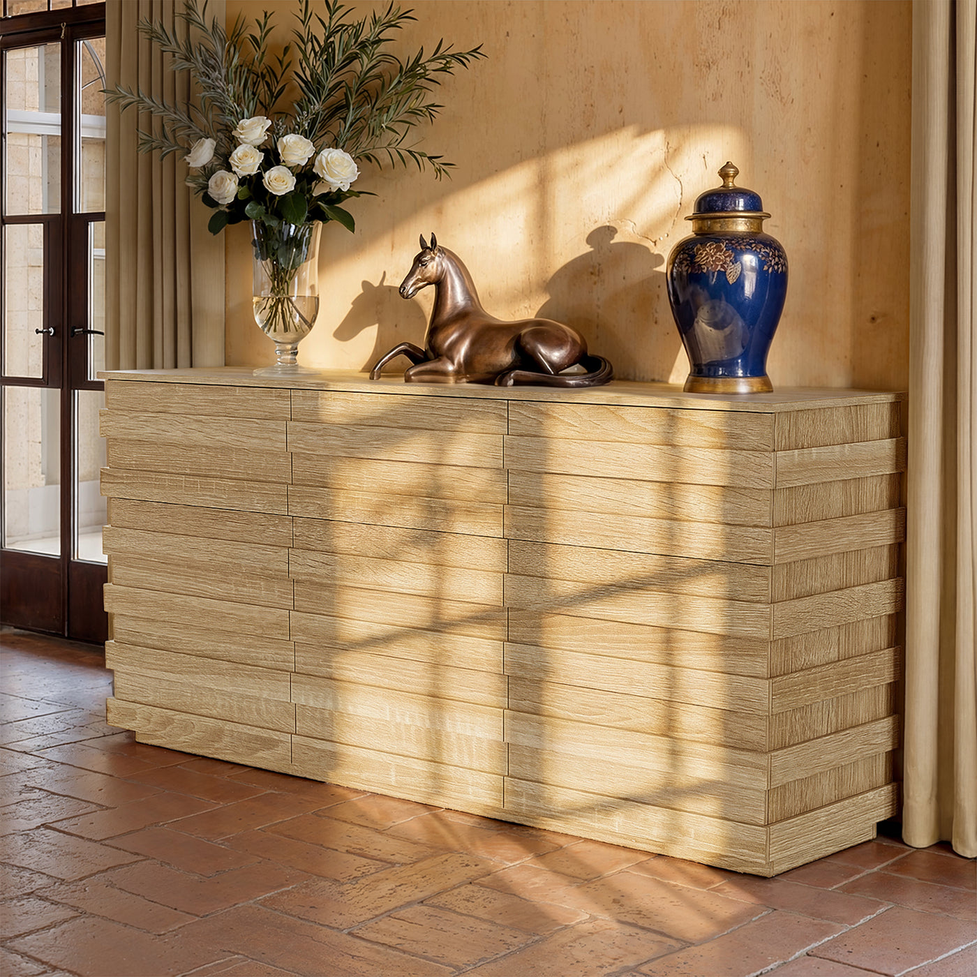 Decorative console table with a vase, horse sculpture, and blue urn against a beige wall