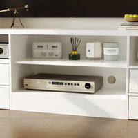 White entertainment console with electronic device, clock, and decorative items.