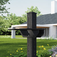 Black wooden bird feeder on a grassy lawn with a house in the background