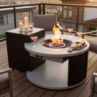 An outdoor fire pit table with a crackling fire, drinks, and snacks, set up on the balcony.