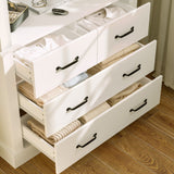 White dresser with open drawers containing folded clothes on a wooden floor.