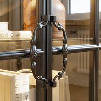 Close-up of a glass door with decorative metal handles, reflecting a room interior