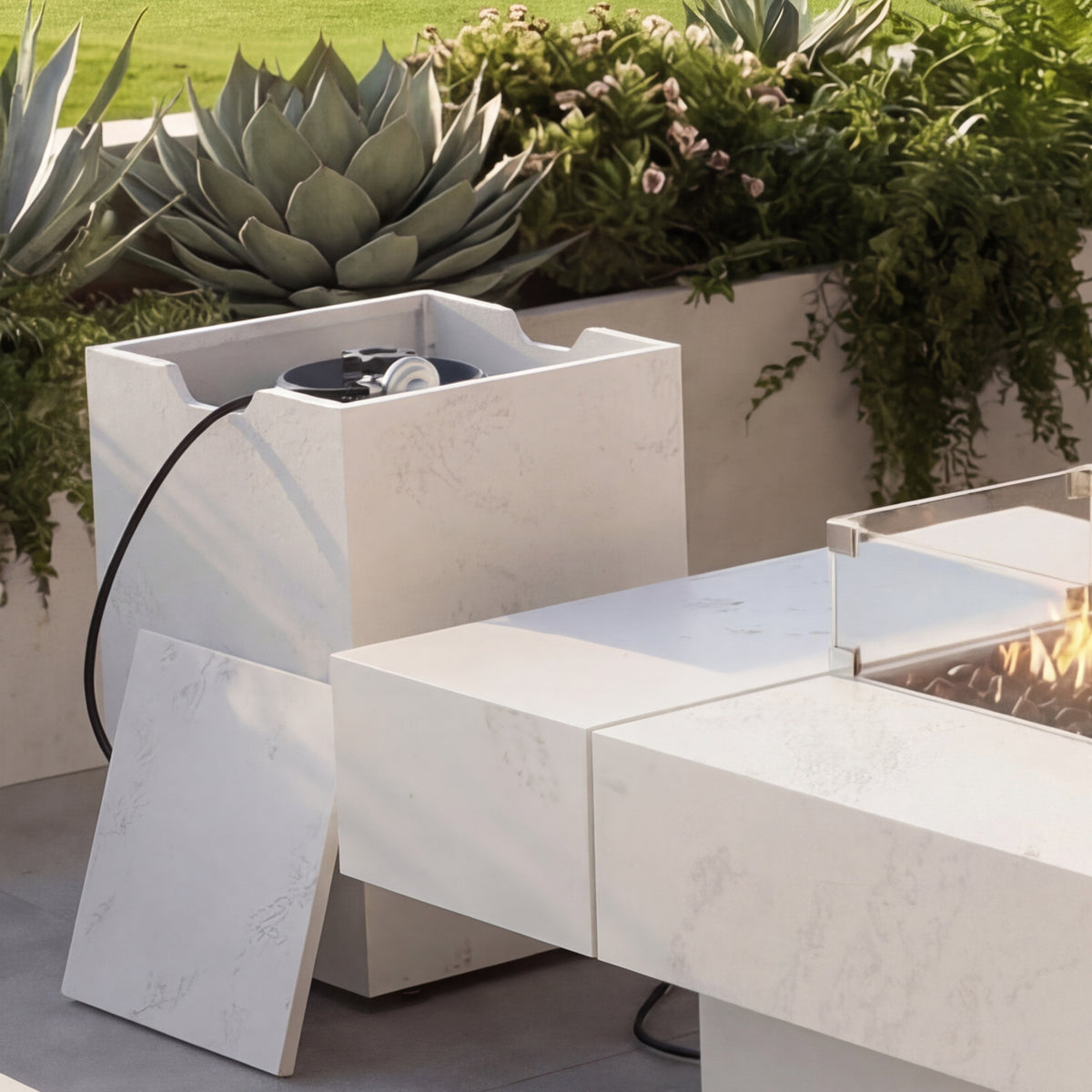 Modern outdoor fire pit table with plants in the background