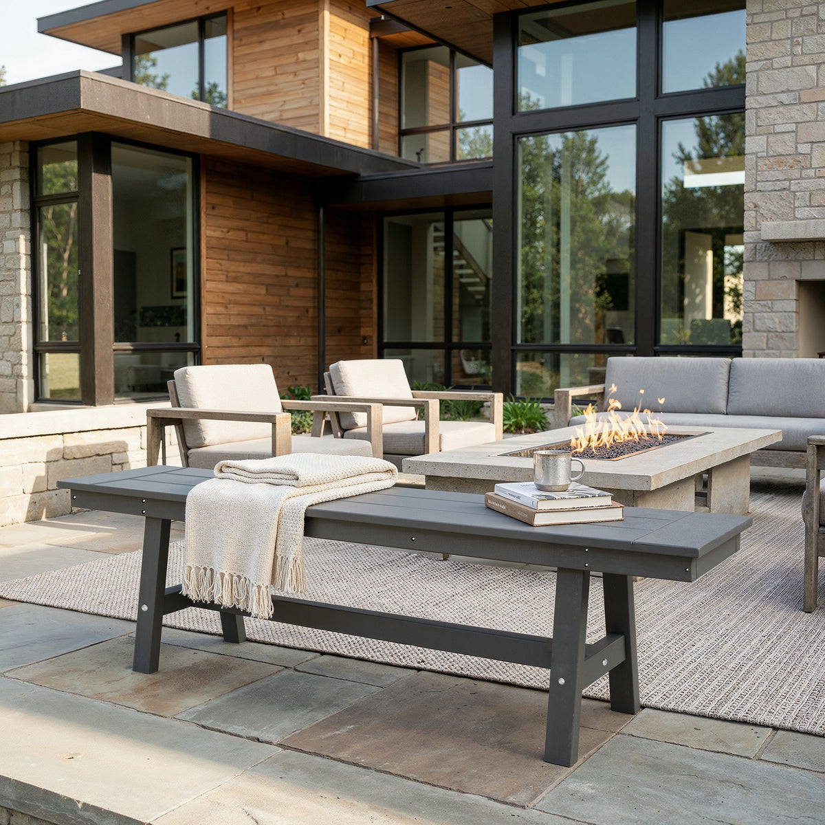 Outdoor patio with modern furniture and fire pit in front of a house.