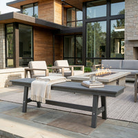 Outdoor patio with modern furniture and fire pit in front of a house.