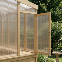 Wooden greenhouse with a transparent polycarbonate roof and walls, set against a natural background.