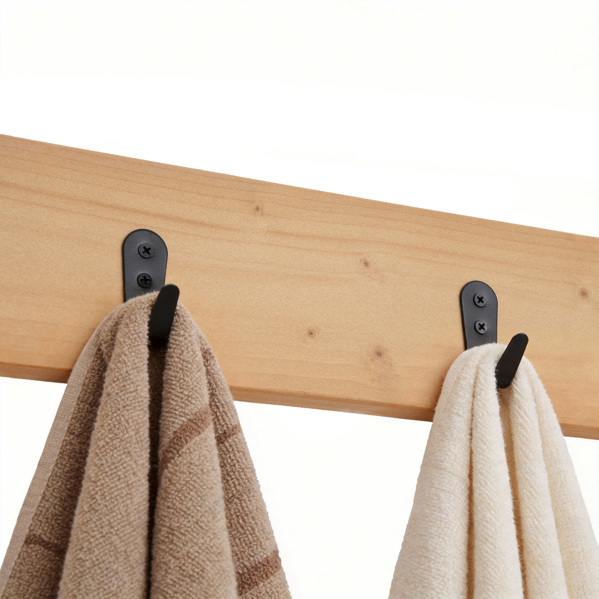 Wooden rack with black hooks holding two towels on a white background