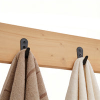 Wooden rack with black hooks holding two towels on a white background