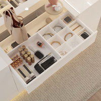 Open drawer with various beauty products including hairbrushes, bottles, and small items on a carpeted floor.