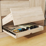 Wooden drawer with various items inside, including a watch and a book, on a wooden floor
