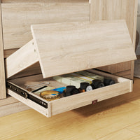 Wooden drawer with various items inside, including a watch and a book, on a wooden floor