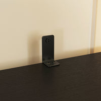 Black phone stand on a dark surface with a light beige wall in the background