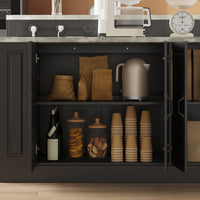 Open black cabinet with kitchen items including a kettle, cups, and decorative jars.