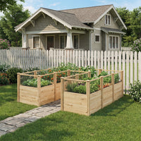 Wooden raised garden beds in front of a house with a white picket fence