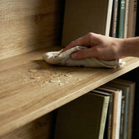 Hand cleaning a wooden shelf with a cloth